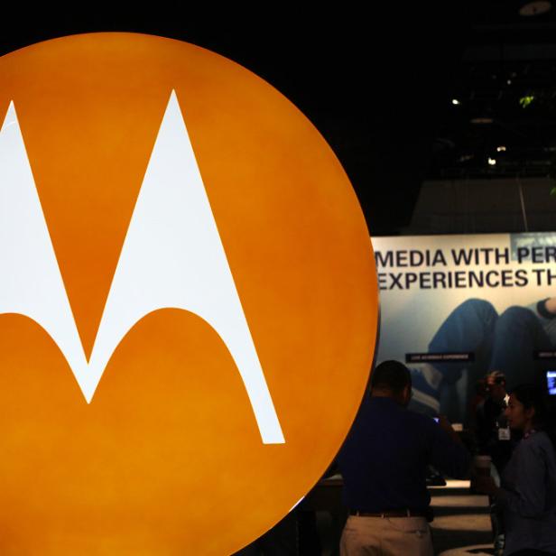 Das Motorola-Logo vor einem Stand mit Bildschirmen und Personen.