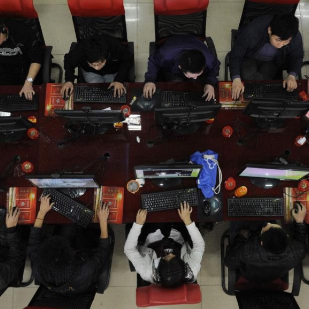 Eine Gruppe von Menschen sitzt an Computern in einem Internetcafé.