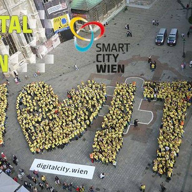 Menschen in gelben T-Shirts bilden das Wort „Wien“ auf einem Platz.