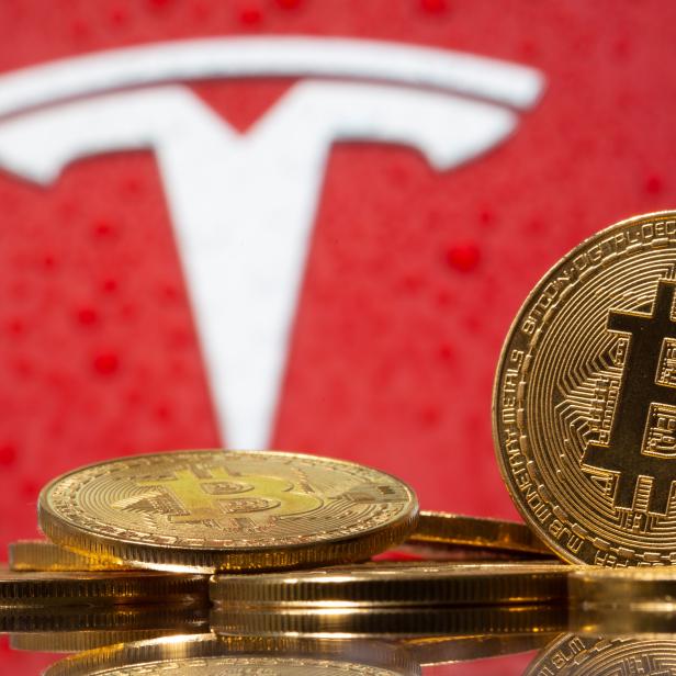 Representations of virtual currency Bitcoin are seen in front of Tesla logo in this illustration