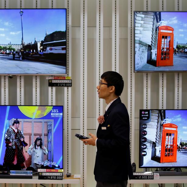 FILE PHOTO: An employee uses his mobile phone in front of LG Electronics' organic light-emitting diode TV sets, which are made with LG Display flat screens, at its store in Seoul