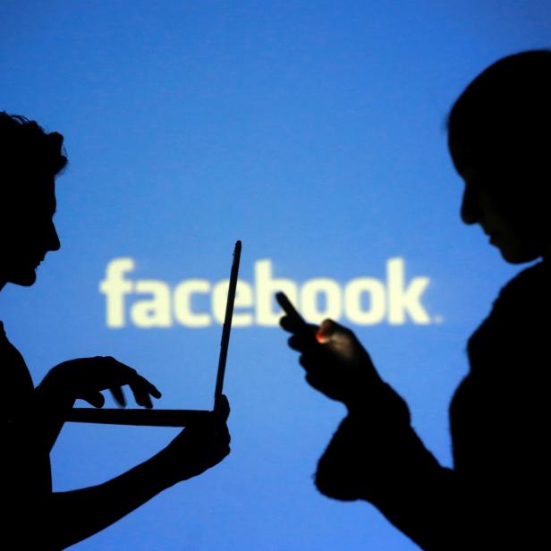 FILE PHOTO: People pose with laptops in front of projection of Facebook logo in this picture illustration taken in Zenica