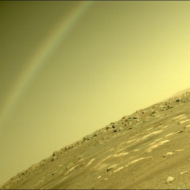 Ein Regenbogen erscheint über einer felsigen Landschaft auf dem Mars.
