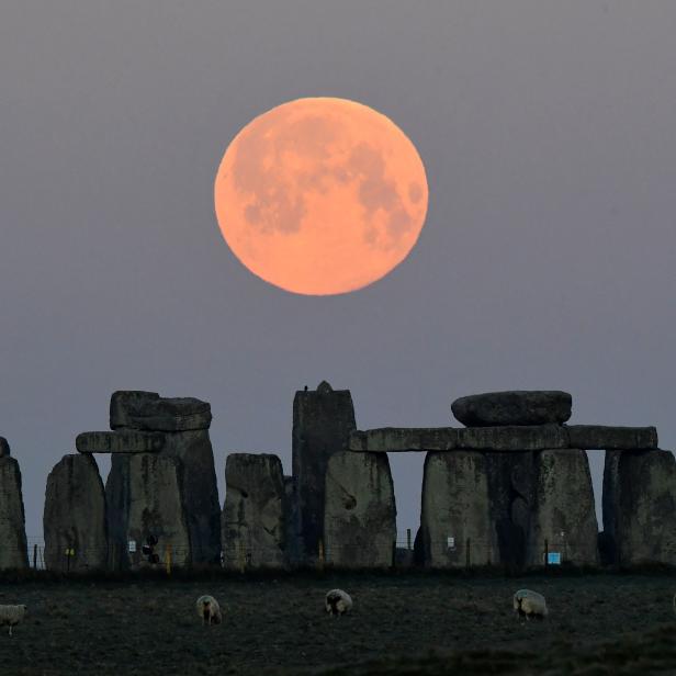 The full moon, known as the "Super Pink Moon", sets behind Stonehenge stone circle near Amesbury