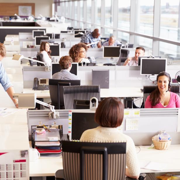 Lässig gekleidete Kollegen unterhalten sich in einem offenen Büro.