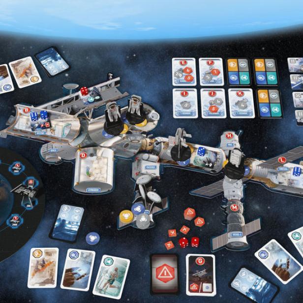 Das Brettspiel „ISS Vanguard“ zeigt eine Raumstation, Spielkarten und Würfel vor einem Weltraumhintergrund.