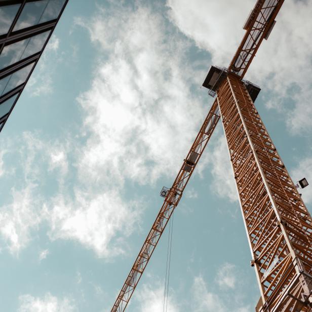 Crane between two buildings with a cloudy background.