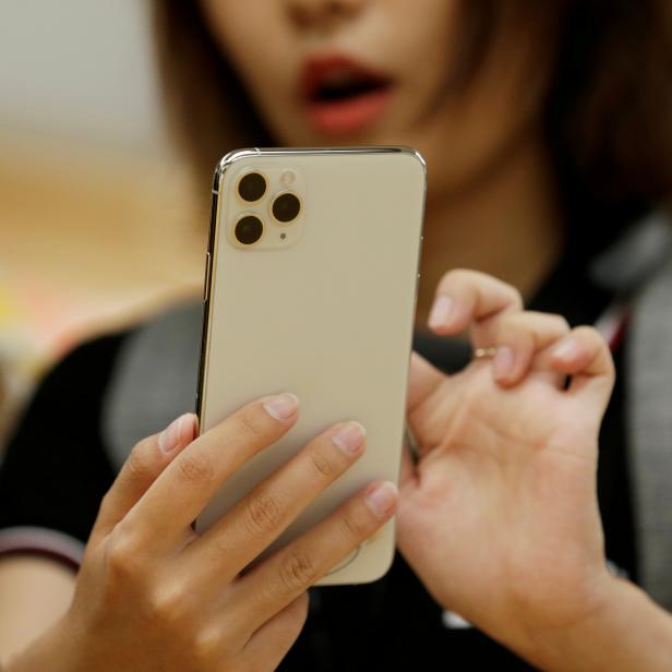 FILE PHOTO: A woman holds an iPhone 11 Pro Max in September 2019 at the Apple Store in Beijing