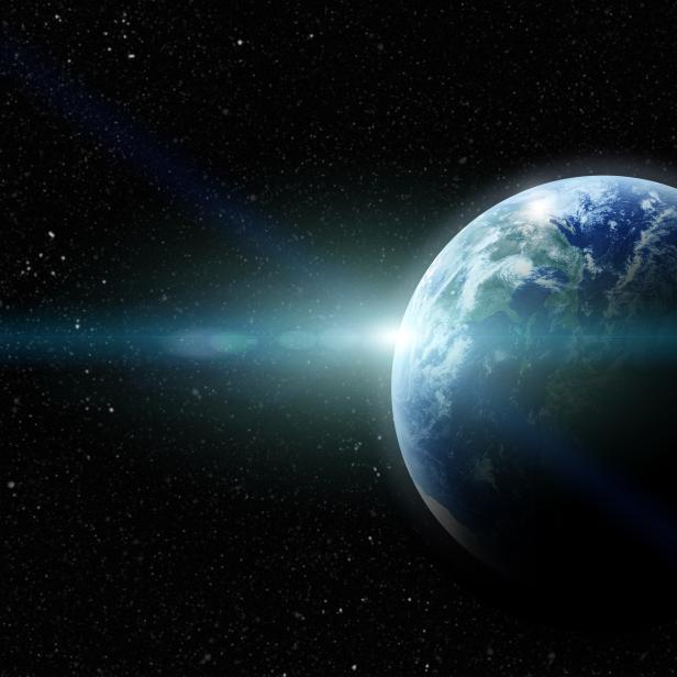 Die Erde vor einem Sternenhintergrund mit einem hellen Lichtstrahl.