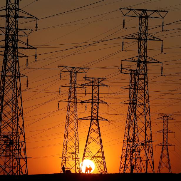 FILE PHOTO: Locals walk past Eskom's electricity pylons as they return from work in Orlando