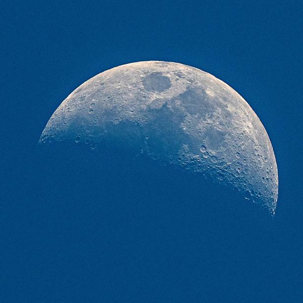 Eine Halbmondphase vor einem tiefblauen Himmel.