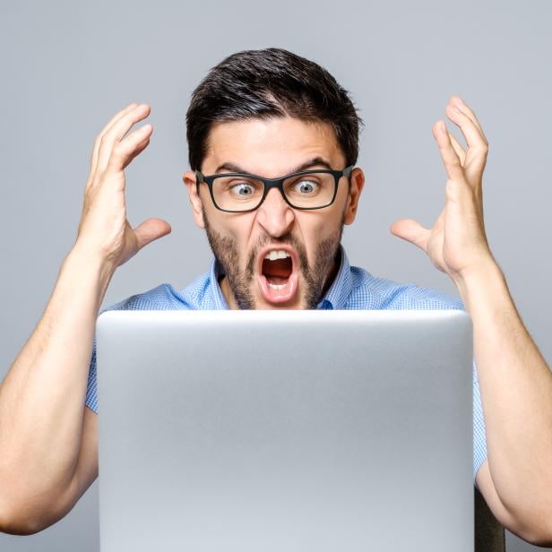 Portrait of amazed man with laptop computer over gray background