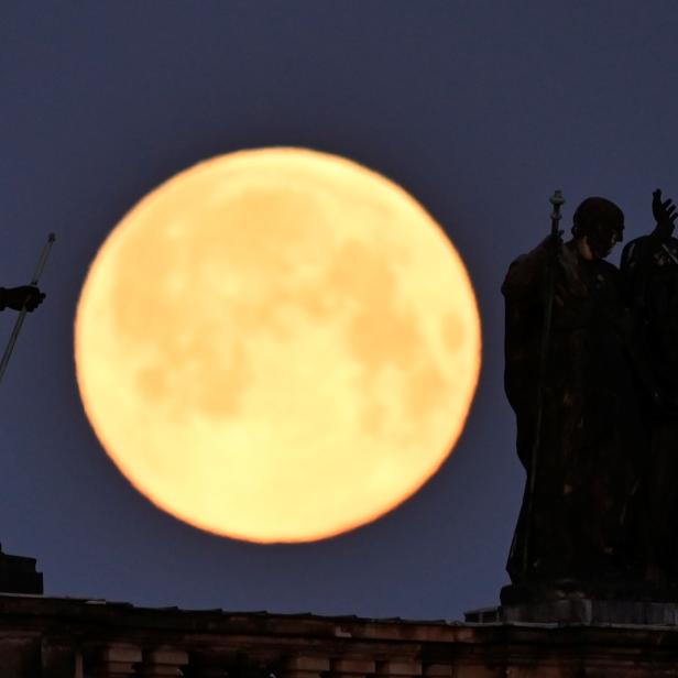 Der Supermond ist hinter den Skulpturen auf dem Dach der Kathedrale in Dresden zu sehen.