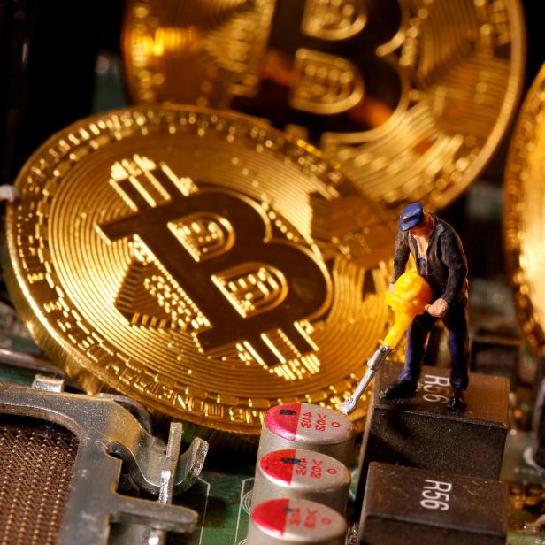 FILE PHOTO: A representation of virtual currency Bitcoin and small toy figures are placed on computer motherboard