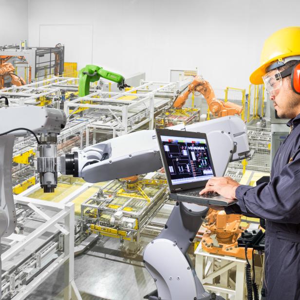 Engineer using computer for maintenance automatic robotic hand machine tool