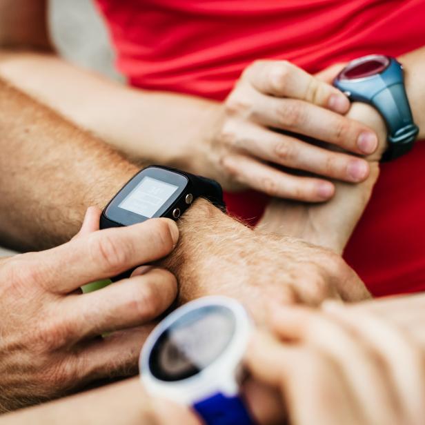 Close Up Of Amateur Athletes Synchronising Smart Watches Together