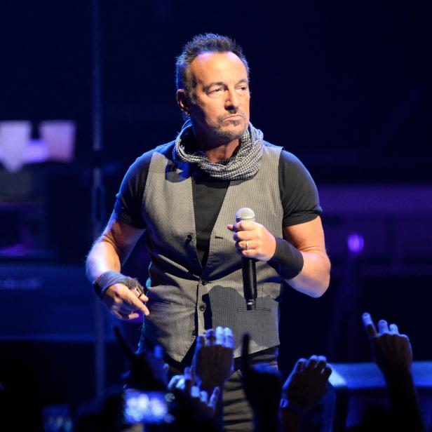Bruce Springsteen tritt vor jubelnden Fans auf einer Bühne auf.