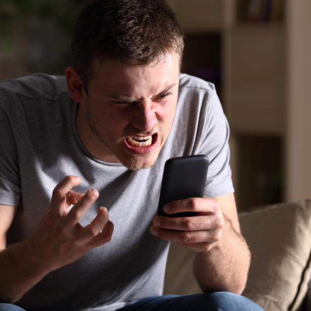 Angry man with a mobile phone at home