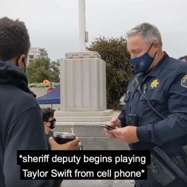 Polizist zückt während eines Gesprächs mit einem Aktivisten sein Smartphone und spielt Musik ab