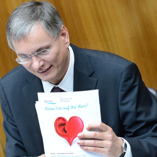 Ein Mann im Anzug liest ein Dokument mit der Aufschrift „Hören Sie auf Ihr Herz!“.