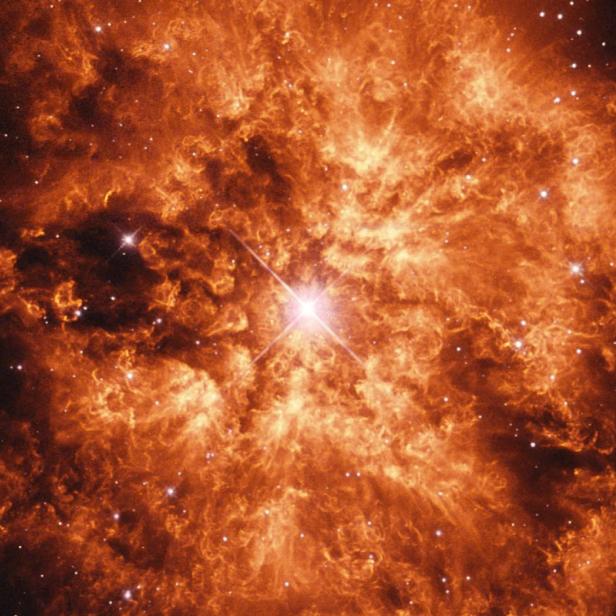 Der Krebsnebel leuchtet in orangefarbenen Tönen vor einem dunklen Hintergrund voller Sterne.