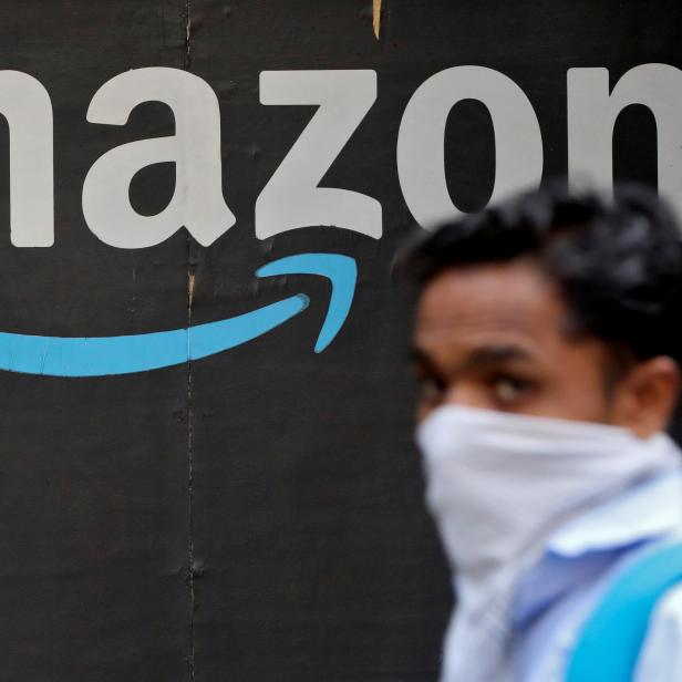 FILE PHOTO: A man walks past an Amazon logo outside the company's collection point in Mumbai