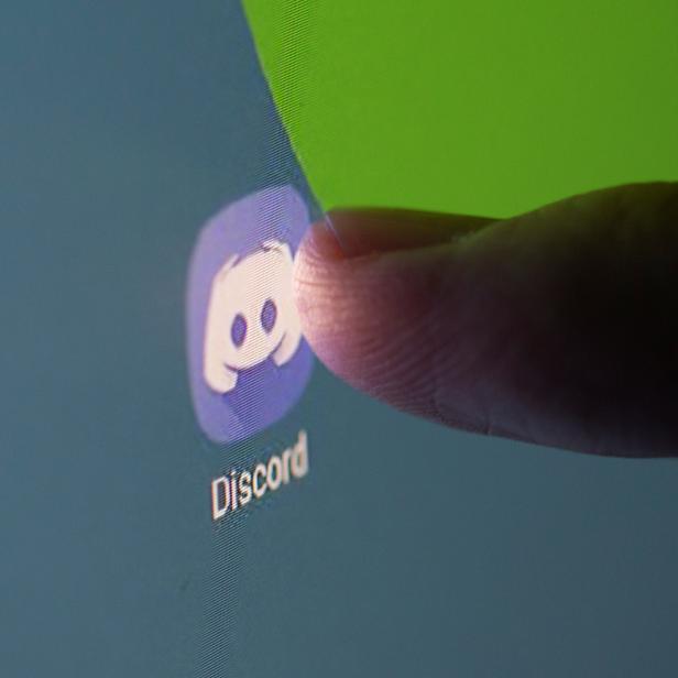 Woman touches Discord app on smartphone in this illustration taken