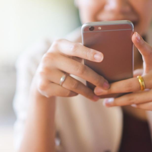 Eine Frau hält ein Smartphone in der Hand. 