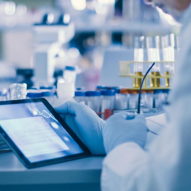 Ein Wissenschaftler im Labor betrachtet Daten auf einem Tablet.