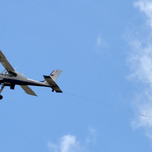 Ein kleines Flugzeug zieht ein langes Banner hinter sich her.