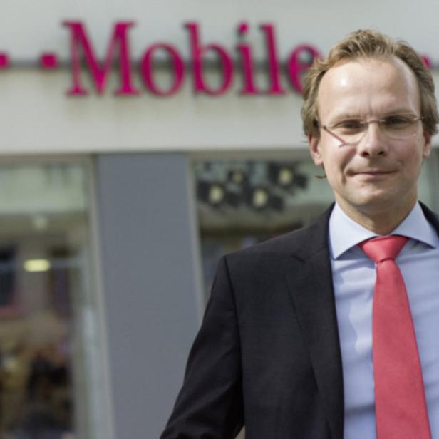 Ein Mann mit Anzug und Krawatte steht vor einem T-Mobile-Geschäft.