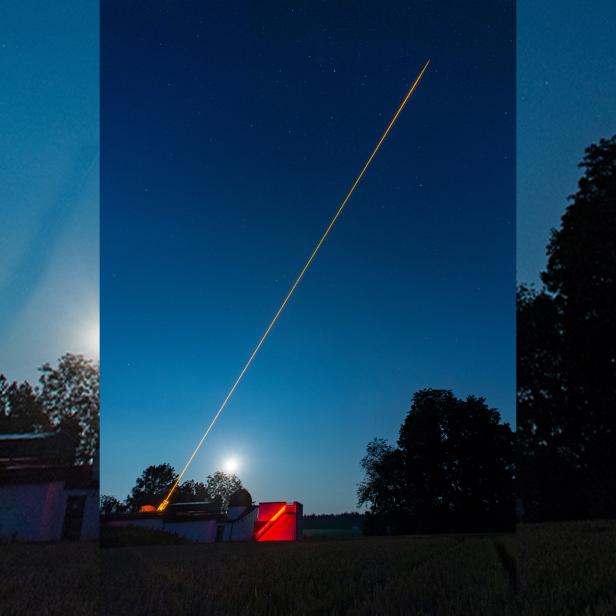 Eine lange, helle Lichtspur zieht sich über einen Nachthimmel mit Sternen.