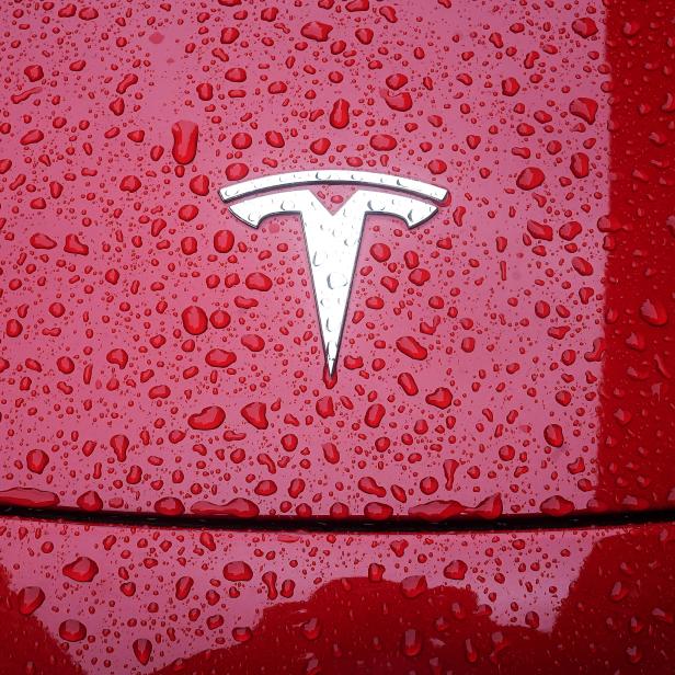 A Tesla logo is pictured on a car in the rain in New York City