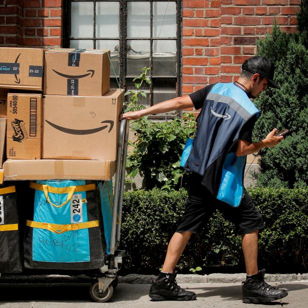 FILE PHOTO: FILE PHOTO: An Amazon delivery worker pulls a delivery cart full of packages during its annual Prime Day promotion in New York