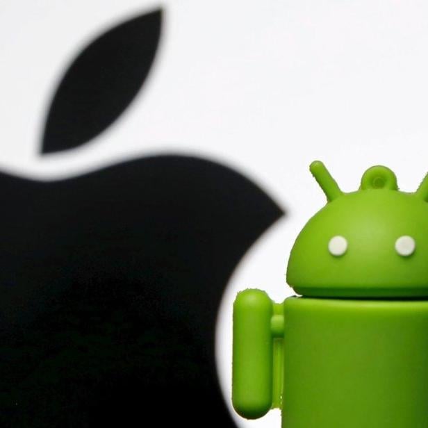 Ein grüner Android-Roboter steht vor dem Schatten des Apple-Logos.