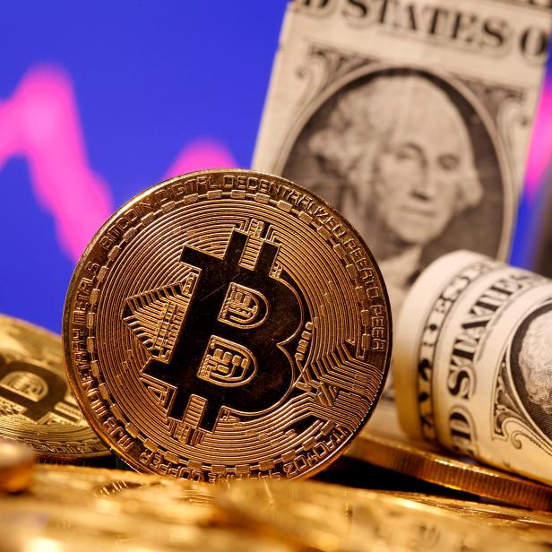 FILE PHOTO: A representation of virtual currency Bitcoin and U.S. One Dollar banknotes are seen in front of a stock graph in this illustration