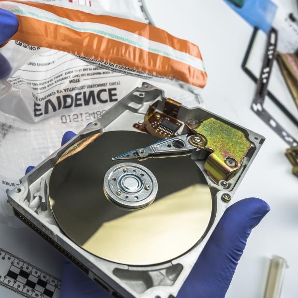 Police expert examines hard drive in search of evidence, conceptual image