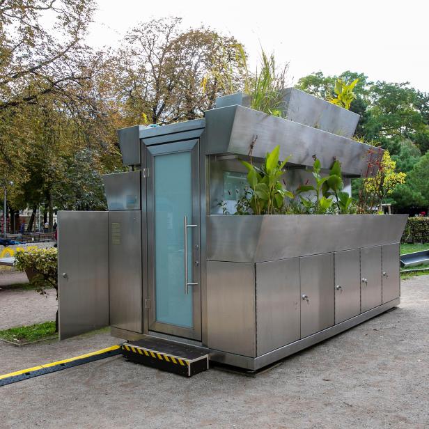 Eine moderne, öffentliche Toilette mit Pflanzen auf dem Dach in einem Park.