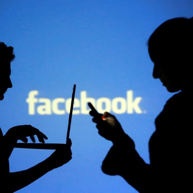 FILE PHOTO: People pose with laptops in front of projection of Facebook logo in this picture illustration taken in Zenica