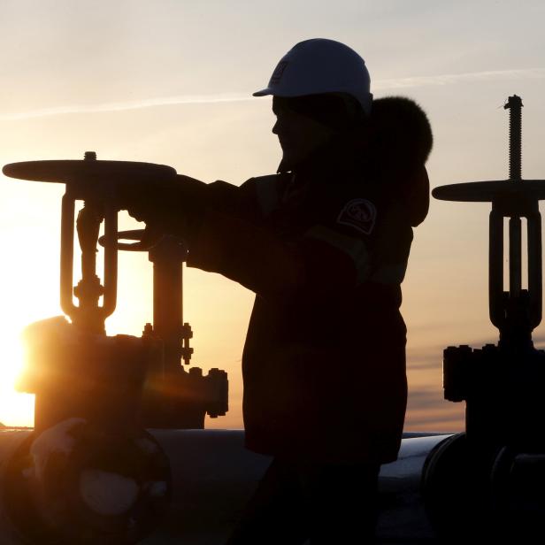 FILE PHOTO: Worker checks valve of oil pipe at Lukoil company owned Imilorskoye oil field outside West Siberian city of Kogalym