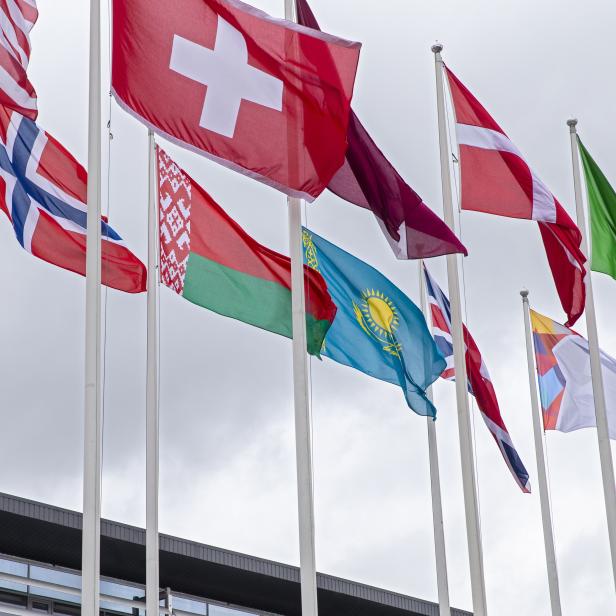 Verschiedene Nationalflaggen wehen vor einem Gebäude, darunter eine Flagge der Eishockey-Weltmeisterschaft 2021 in Riga.