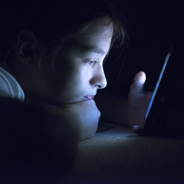 Teenager sending email from smart phone in her bed