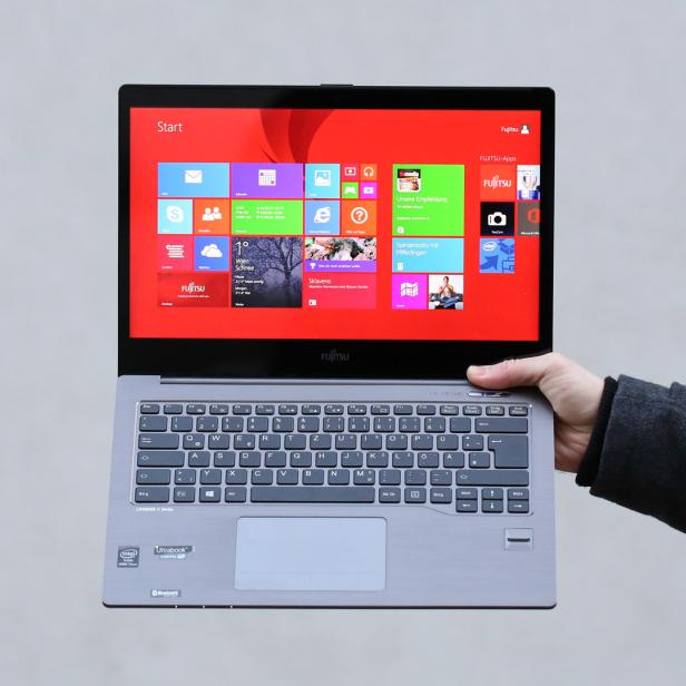 Eine Hand hält ein Fujitsu Lifebook mit Windows-Startbildschirm.