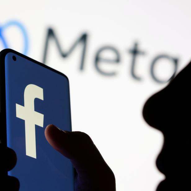 FILE PHOTO: Woman holds smartphone with Facebook logo in front of a Meta logo in this illustration picture