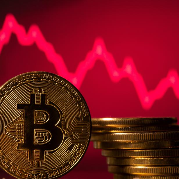 A representations of virtual currency Bitcoin is seen in front of a stock graph in this illustration