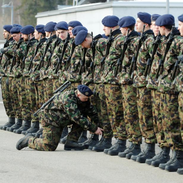 A soldier of the Swiss Army cleans the boots of a member of a honor guard at the Swiss Air Force base in Meiringen