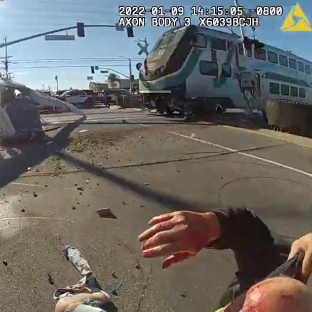 A screen grab from a police body camera video shows the pilot of a plane that crashed on railway tracks being rescued by Los Angeles Police Department officers moments before a train hit the aircraft in Los Angeles