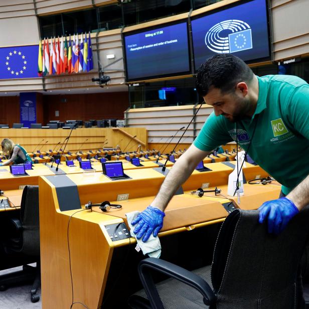 A worker cleans desks inside the hemicycle ahead of a plenary session of the European Parliament in Brussels
