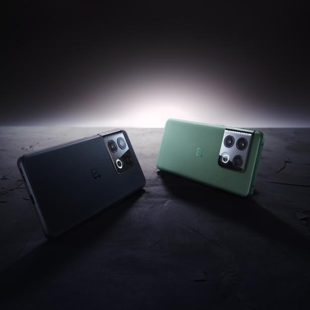 Zwei OnePlus-Smartphones in Schwarz und Grün liegen auf einer dunklen Oberfläche.