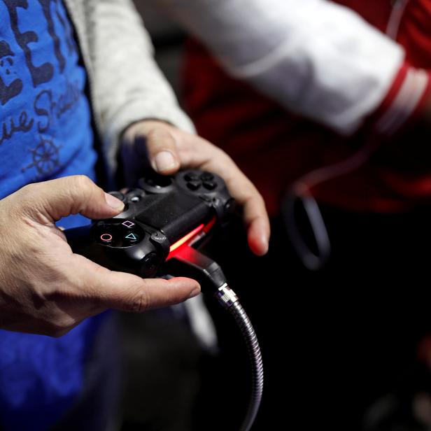 FILE PHOTO: Visitors play games on PlayStation 4 (PS4) at the Paris Games Week, a trade fair for video games in Paris